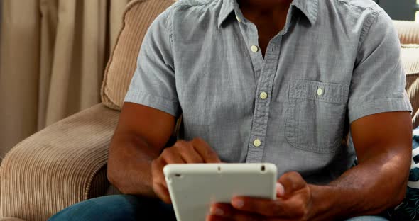 Handsome man using digital table in living room 4k alt