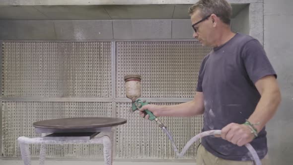 Workman using airbrush for applying flame retardant to wood detail ensuring fire protection alt