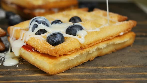 Pouring Viennese Waffles with Condensed Milk with Blueberries