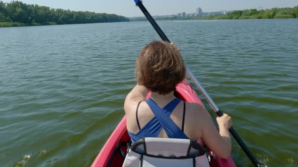 Woman Swims on a Kayak on a Calm River alt