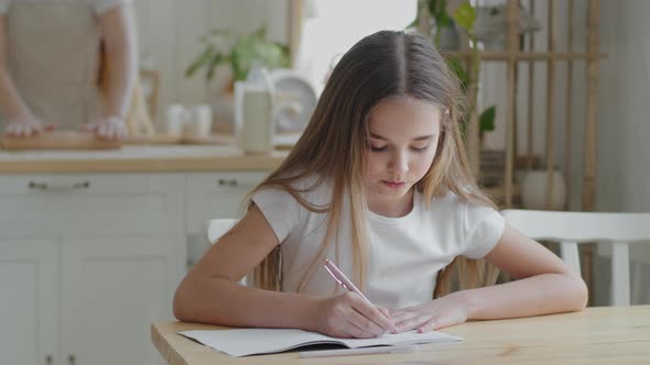 Teenager Girl Child Schoolgirl Pupil Sitting at Home at Table in Kitchen Doing Homework Writing alt