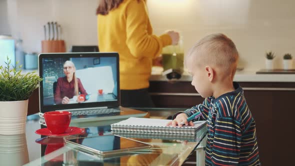 Boy Having Online Video Schooling While Mom Giving Him Fresh