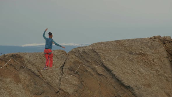 A Young Woman Is on the Slackline at High Altitude. alt