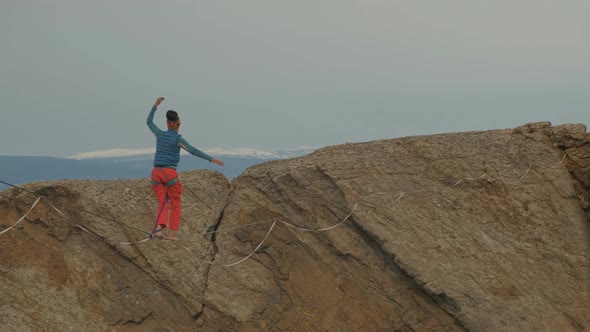 A Young Woman Is on the Slackline at High Altitude.
