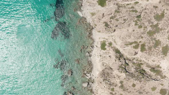 Overhead Top Down Aerial Flight Over Greek Island Milos Turquoise Blue Ocean with Rocky Cliff Coast alt