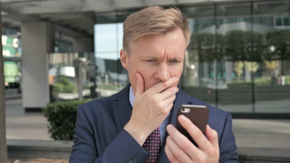 Shocked Businessman Upset for Loss on Smartphone alt