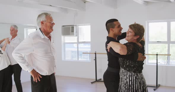 mixed race male dance teacher taking a ballroom dancing class at a dance studio alt