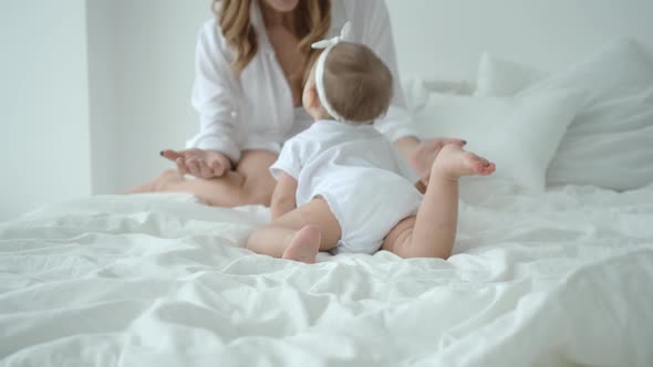 Cute Infant Baby Girl Climbing On The Bed And Crawling To Her Mom