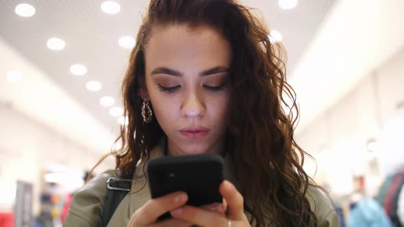 A Happy Girl Looks at the Screen of Her Smartphone alt