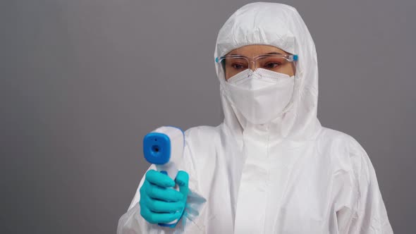 doctor in protective PPE suit scanning with infrared thermometer, IR Thermoscan