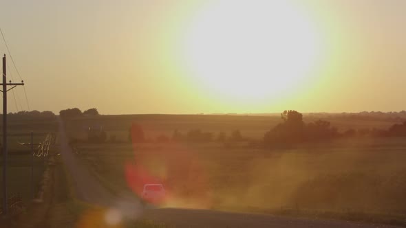 Static view of fields with the sun above the horizon, as truck drives by. alt