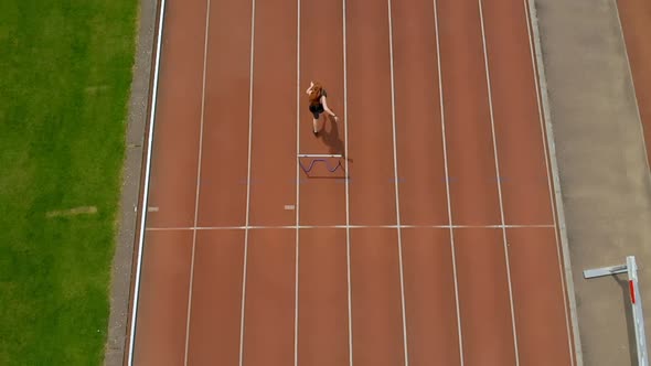 Female athletic jumping over hurdle on sports track 4k alt
