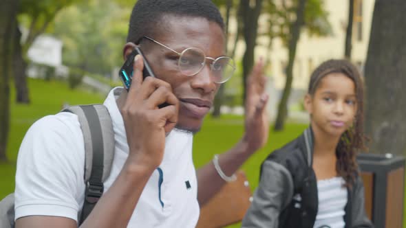 Close-up of African American Man Talking on the Phone As Bored Little Girl Trying To Draw His alt
