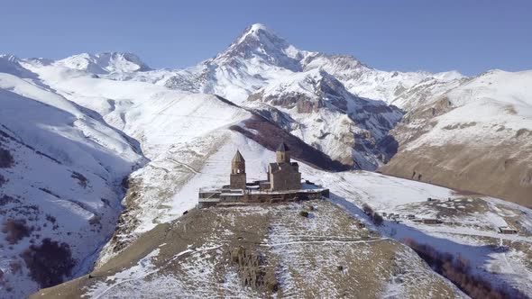 Aerial Footage of Lonely Old Medieval Gergeti Trinity Church in Winter Mountains in Kazbegi Georgia