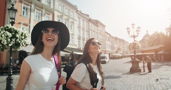 Female Tourists with Backpacks Walking in City