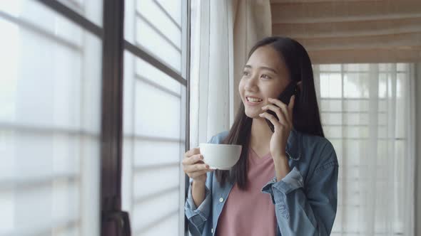 Young Asian woman drink coffee and talking on Phone with friends.