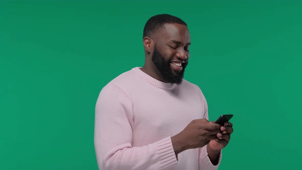 Young Afro American Man in Casual Chatting on Smartphone and Smiling on Green Screen Chroma Key alt