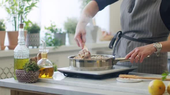 Person stirring hot veal shanks in frying pan alt