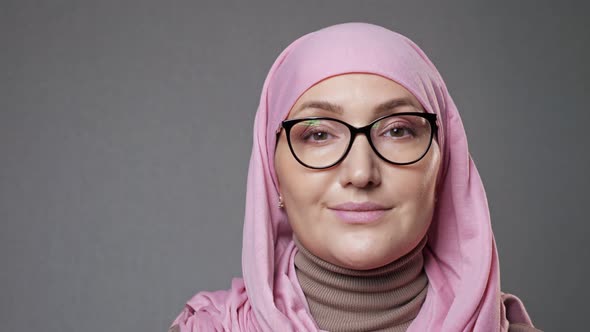 Young Woman in Glasses and Hijab Smiles Looking Into Camera alt