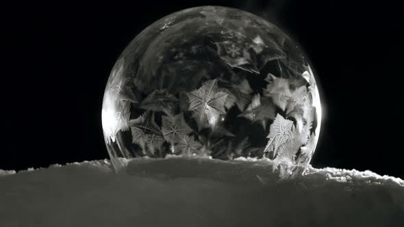 Ice Bubble with Icy Crystals Freezing Fast in Cold Winter in Black Background alt