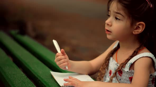 Little Girl Draws On Paper. Baby Girl Small Kid Enjoying Creative Art. Child Painting With Pencil. alt