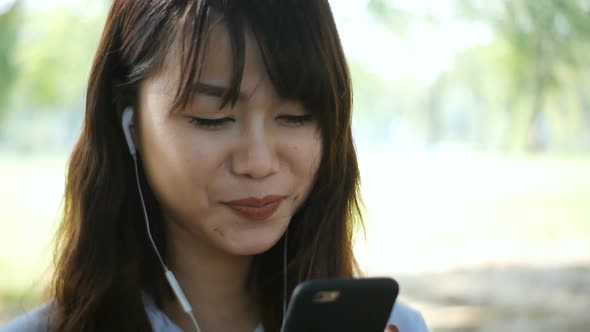 woman is reading pleasant text message on mobile phone while sitting in the park in warm spring alt