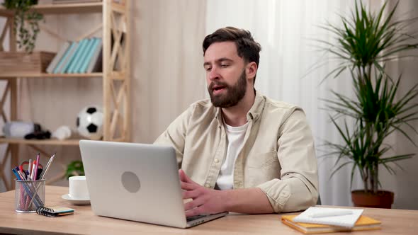A Man Works at a Laptop While Sitting at a Table at Home alt