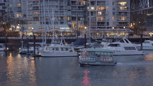 Small ferry cruising around Granville island at night alt