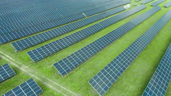 Flight Along Solar Panel on the Green Field. Solar Power Station for Production of Green Energy alt