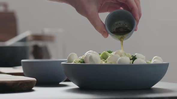 Slow Motion Man Pour Dressing Over Salad with Kale Mozzarella Avocado and Cherry Tomatoes alt