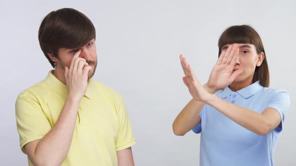 Young Man Touching His Eye with Dirty Finger and Young Woman Looking Surprised and Terrified Showing alt
