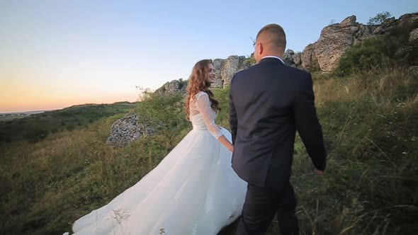 Bride and Groom Walking on the Grass Field in Love with Her Wedding Day alt