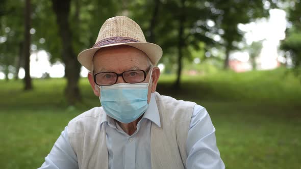 An Old Man Was Vaccinated and Sitting in a Medical Mask on a Bench alt