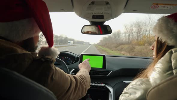 Young Couple in Santa Hats Use Green Screen Display in Car alt