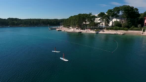 Aerial view of two women practicing stands up board, Losinj coastline, Croatia. alt