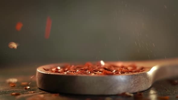 Flakes of Red Hot Chili Pepper in Wooden Spoon Closeup on a Kitchen Table alt