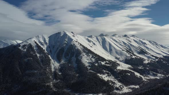 Air Flight Through Mountain Clouds Over Beautiful Snowcapped Peaks of Mountains and Glaciers alt