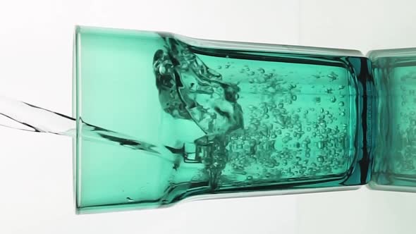 Vertical Video Crystal Clear Water Pouring Into Green Faceted Glass