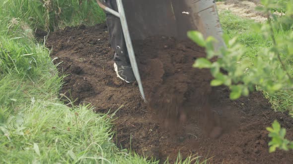 Emptying wheelbarrow of compost over soil for planting alt