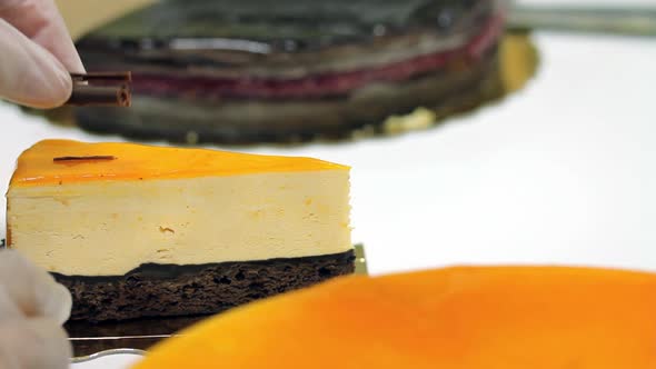 A confectioner decorates a piece of cake with a chocolate flake