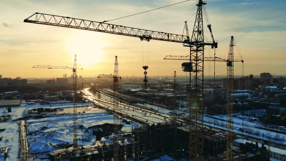 Sunset Cityscape with Cranes in the Building Lot alt