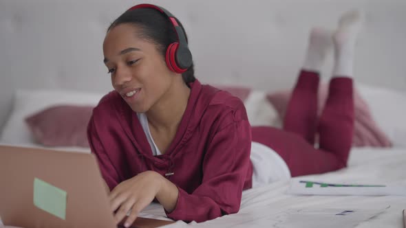 Joyful Laughing Young Woman in Headphones Greeting Colleagues in Video Chat Waving and Talking alt