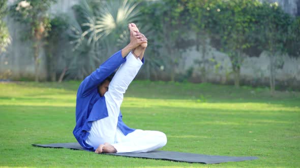 Indian man doing Krounchasana or Heron Yoga Pose in an Indian traditional outfit Kurta Pajama alt