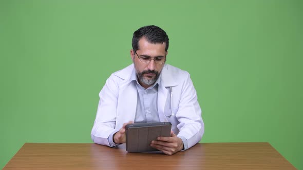 Handsome Persian Bearded Man Doctor Thinking While Using Digital Tablet