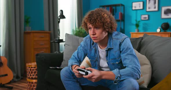 Teen Boy is Enjoying Video Game Using Controller Concentrated on Interesting Activity in Apartment alt