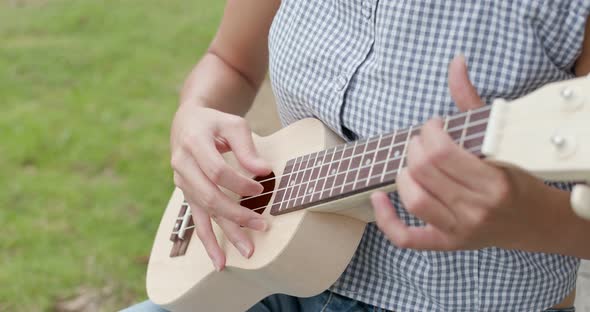 Woman Play a Song on Ukulele and Sitting on The Grass alt