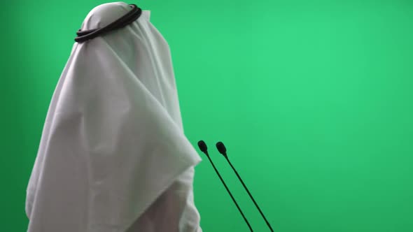 Back View of an Anonymous Arab Man in a White Kandura Standing on a Green Background the Lecturer alt