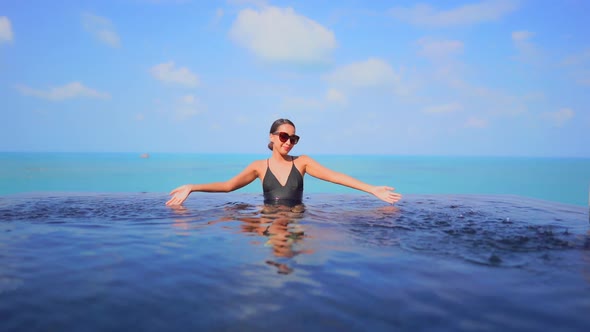 Young asian woman enjoy around outdoor swimming pool for leisure alt