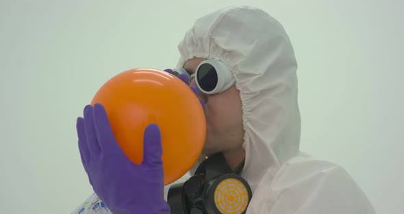 Man in a chemical protection suit inflates an orange balloon alt
