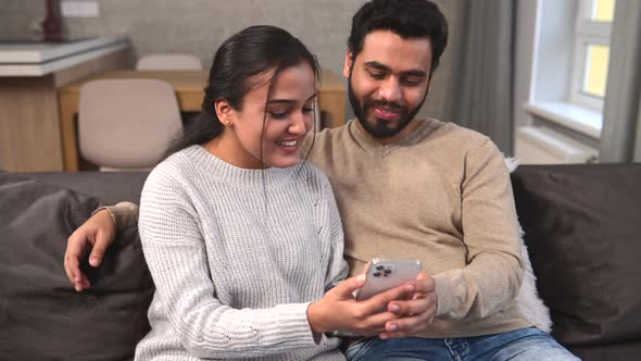 Indian Couple with Smartphone on the Couch Spending Leisure Time in Social Networks